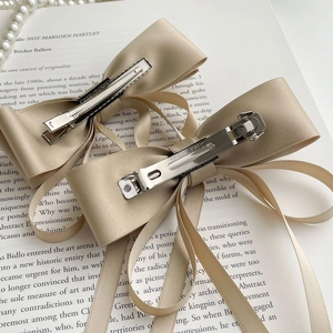 Détail de l'ensemble de barrettes noeud en satin champagne avec clip en métal chic