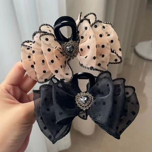 Detailed view of polka dot bow hair clips with heart gemstones and sparkling rhinestones