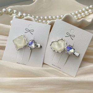 Close-up of elegant heart and square crystal hair clips on a pearl and silk background