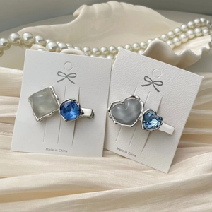 Detail view of heart-shaped crystal hair clips on satin background with pearls