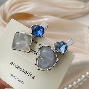 Detailed close-up of heart and square crystal hair clips on luxury champagne satin fabric
