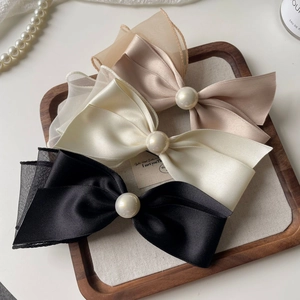 Detailed set of elegant satin bow hair clips in black and cream with central pearl accents
