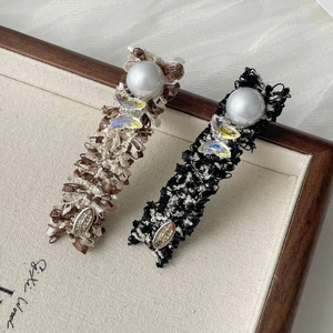 Elegant tweed bow and pearl hair clips set with butterfly accents on a wooden display tray