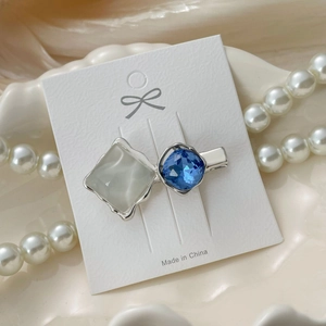 Detailed view of luxury heart hair clip with blue crystal and cat eye stone on shell tray
