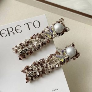 Close-up of tweed butterfly hair clips with faux pearls and handmade metal tag detail