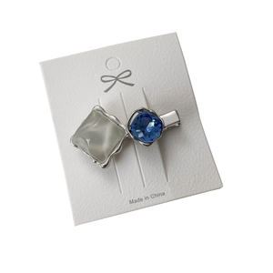 Silver metal hair clip with blue crystal and grey heart resin on display card