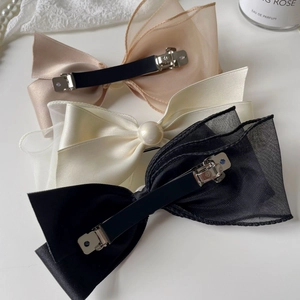 Detail of elegant satin bow hair clips set with pearl accents in three various colors