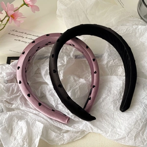 Détail de serre-têtes en satin rose poudré avec motifs cœurs et noir classique