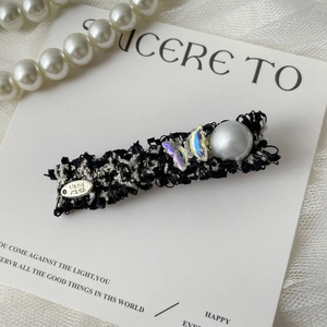 Detail of tweed hair clip featuring iridescent butterflies and a large grey pearl on card