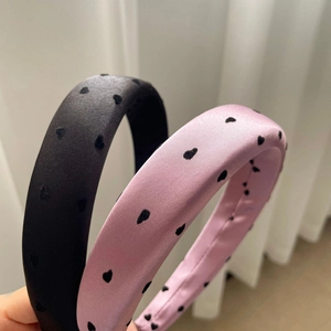 Détail du serre-tête rembourré en satin avec motifs de cœurs noirs et roses