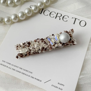 Detail of tweed hair clip with large pearl, crystal butterfly and handmade metal tag
