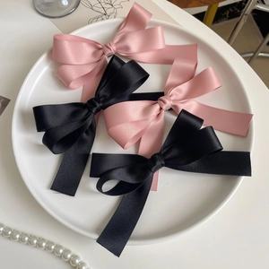 Close-up of pink and black satin ribbon hair bows neatly arranged on a white tray