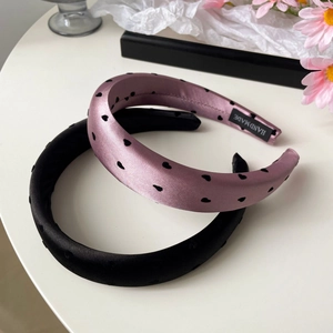 Lot de serre-têtes en satin rose à motif cœur et noir sur une surface blanche élégante
