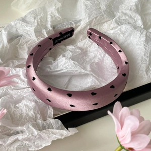 Vue détaillée du serre-tête en satin rose avec motif cœur et étiquette fait main