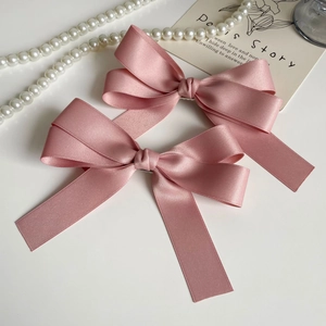 Detail of pink satin bow hair clips with long ribbon streamers and silky texture