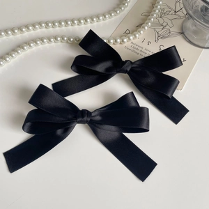 Detail view of two vintage black satin bow hair clips with elegant silk texture