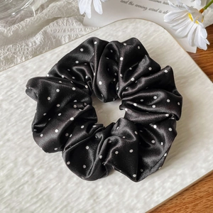 Macro detail of French satin black polka dot scrunchie with elegant soft texture