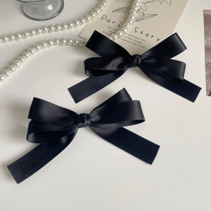 Detail of dual-layered black satin ribbon bow hair clips with elegant silk finish