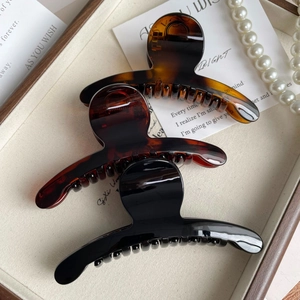 Lot de trois grandes pinces à cheveux vintage ambre et noir sur un plateau à bijoux