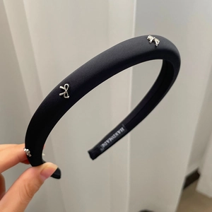 Detail eines handgefertigten schwarzen Satin-Haarreifs mit eleganten silbernen Metallschleifen
