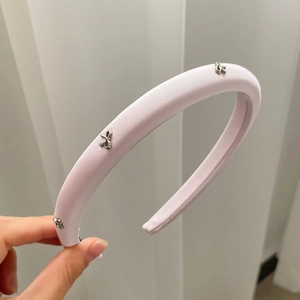 Nahaufnahme von rosa gepolstertem Satin-Stirnband mit drei silbernen Metallschleifen