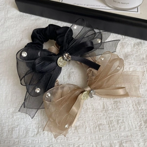 Détail de chouchous nœuds en organza noir et champagne avec des strass brillants
