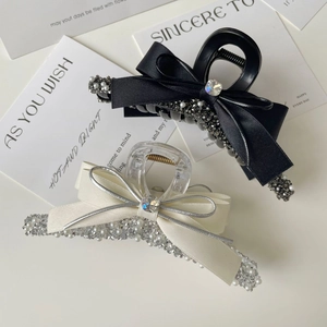 Elegant bow hair claws with satin ribbon, pearls, and rhinestones on a white background