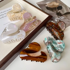 Detailed view of six diverse acetate claw clips featuring marble patterns and gold accents