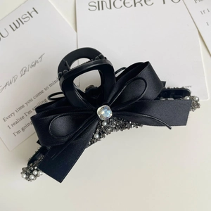 Detailed shot of black ribbon bow hair claw with pearls and rhinestone on white background