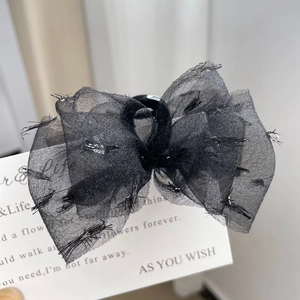 Vue macro d'un nœud à cheveux en tulle noir avec paillettes argentées sur fond blanc