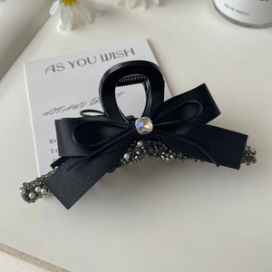 Detail of black satin bow hair claw clip with grey rhinestones and white pearls inlay