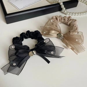 Détail de chouchous nœuds en organza noir et champagne avec strass et charms métalliques