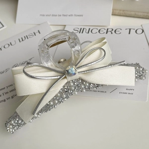 Detail of transparent hair claw with cream bow, silver trim, and pearl rhinestone accents