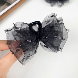 Détail de la pince à cheveux noeud en tulle noir avec paillettes argentées et bords vintage