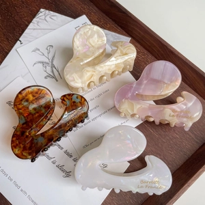 French acetate hair claws in tortoise, marble, and pearl finishes on vintage wooden tray