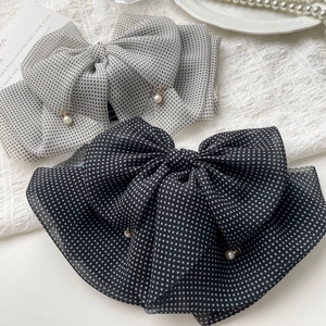 Detail of polka dot chiffon bow hair clips with elegant pearl pendants in a French style