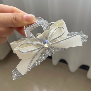 Detail of cream satin bow hair claw clip with silver edges, pearls and rhinestones