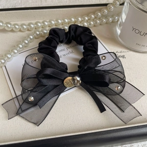 Détail d'un chouchou noeud en organza noir avec strass et emblème doré élégant