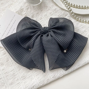 Detailed macro view of polka dot chiffon bow hair clip with elegant pearl accents