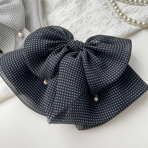 Detail of black polka dot chiffon bow hair clip with elegant hanging pearl pendant