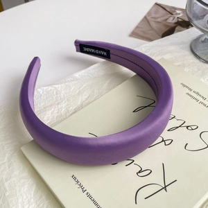 Detail of purple satin padded headband with handmade label on an aesthetic book