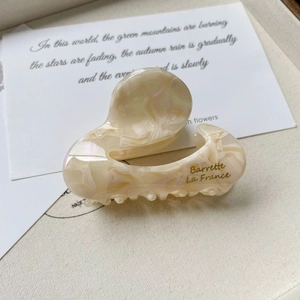 Detail of cream marble acetate hair claw clip with golden Barrette La France text