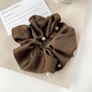 Detailed macro shot of dark brown satin scrunchie with white pearl embellishments