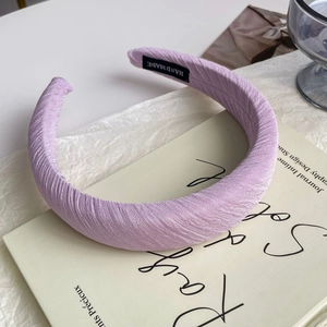 Detailed macro view of handmade lavender purple satin pleated headband texture with label