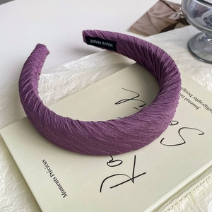 Detail shot of a romantic purple satin headband with a handcrafted woven label