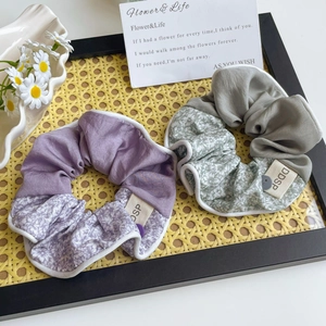 Détail de chouchous à fleurs et unis violets avec bouton et étiquette sur plateau