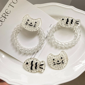 Gros plan sur élastiques spirale transparents et pinces chat mignon sur assiette blanche
