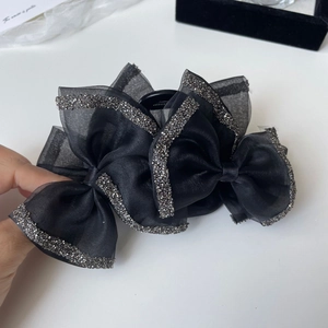 Detail view of black layered bow hair claw clip with shimmering silver rhinestone edges