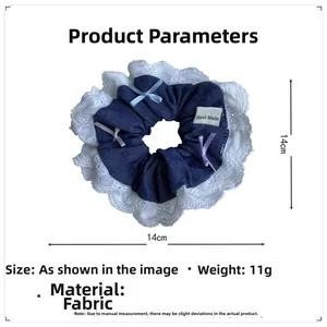 Détail d'un chouchou en denim avec dentelle blanche, mini nœuds et étiquette artisanale
