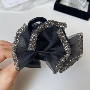 Macro shot of elegant black mesh bow hair claw clip with shimmering silver rhinestones